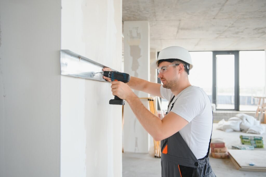 Construction worker installing metal profile for interior partition wall, while building a new house